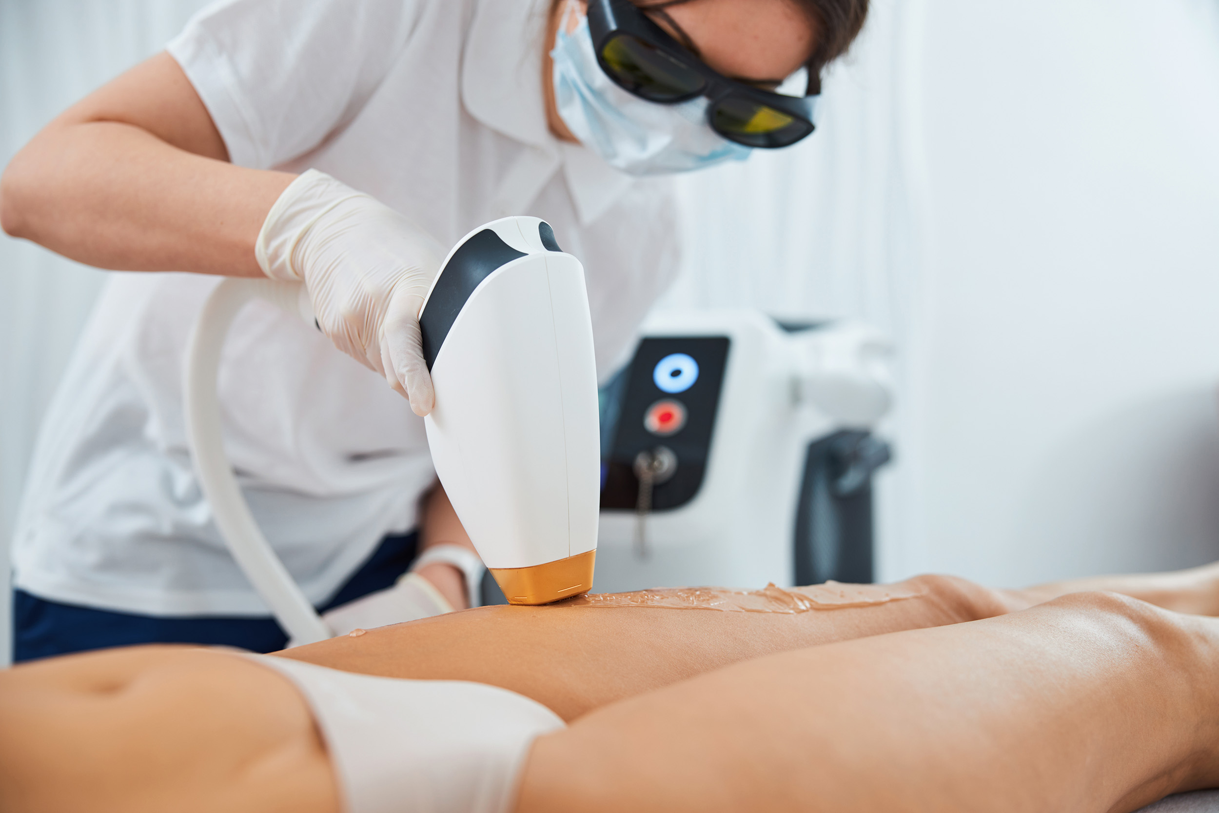 A woman getting laser hair removal on her legs at a med spa.