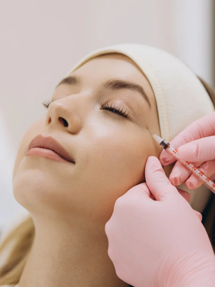 Woman receiving facial injection treatment at medical spa with practitioner wearing pink gloves - in Tampa, FL