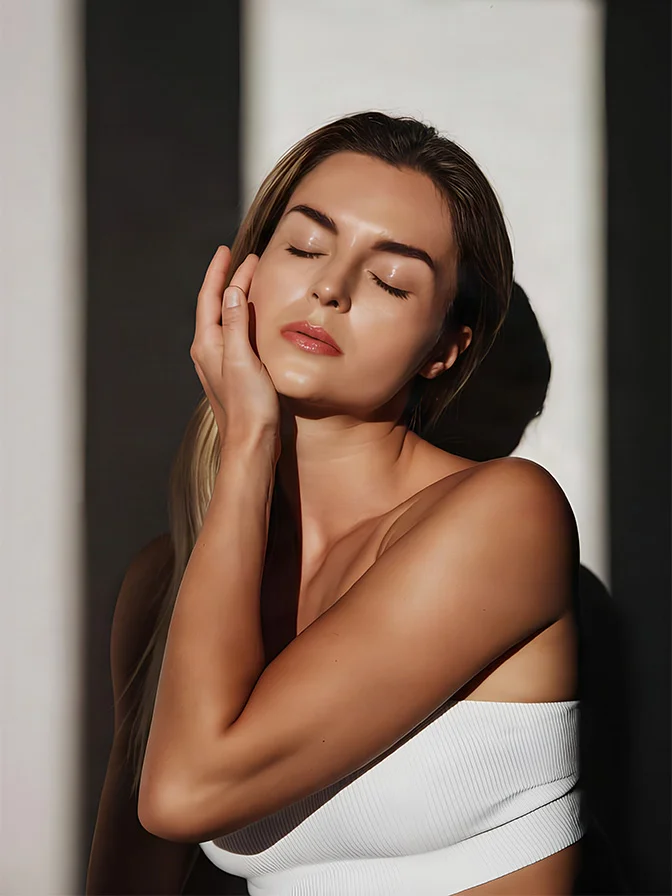 Woman with glowing skin touching face in white top, eyes closed in serene beauty portrait - C02 lift masks in Tampa, FL
