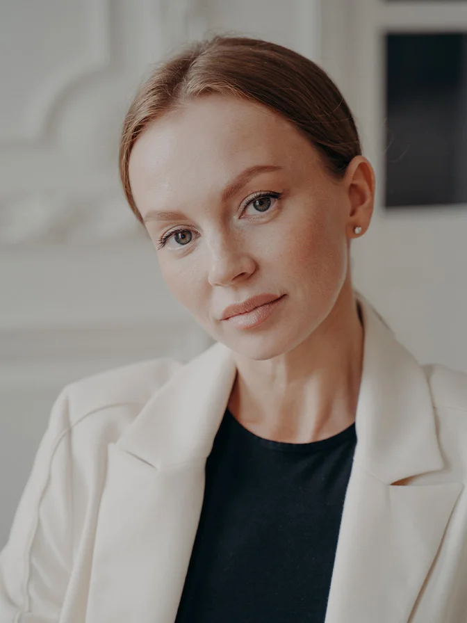 Professional woman in white blazer and black top with confident smile in modern office setting - Hormone replacement in Tampa, FL