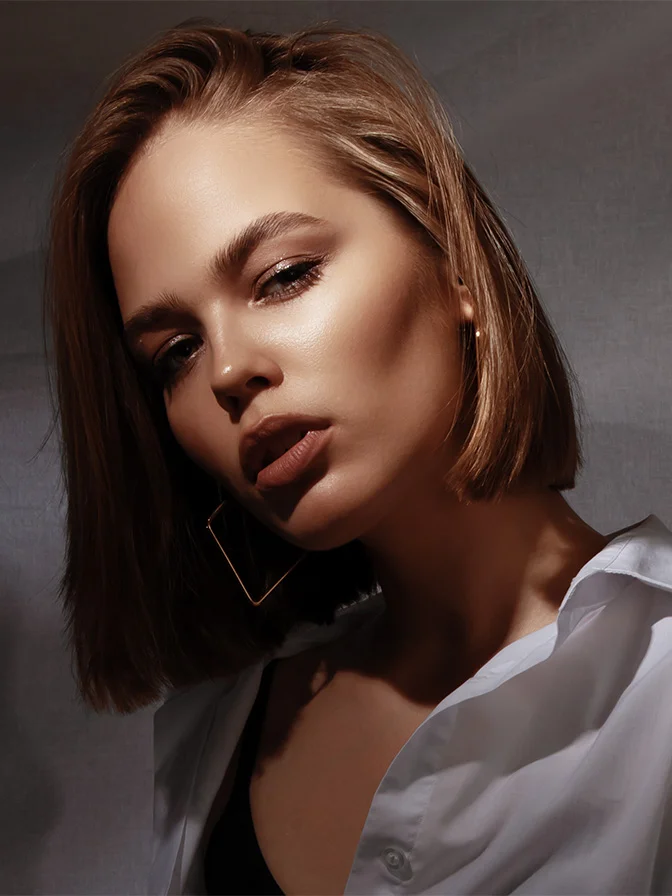 Woman with short blonde bob and natural makeup in white shirt against gray background in portrait style - Latisse in Tampa, FL