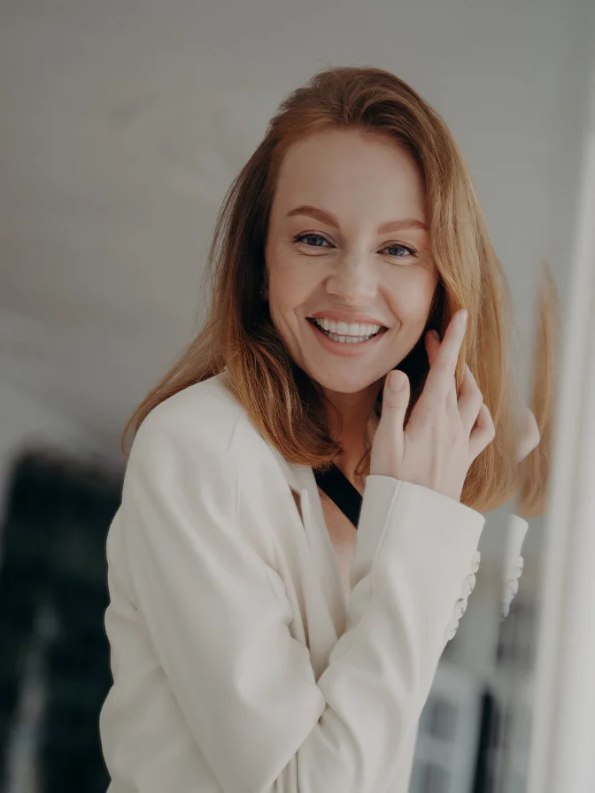 Smiling woman with long red hair wearing white sweater in bright indoor setting - Obagai in Tampa, FL