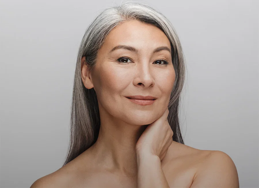 Mature woman with gray hair touching face showing natural beauty and healthy aging skincare